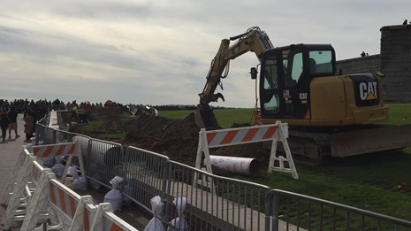 An excavator helps in installing the new fencing on Liberty Island.