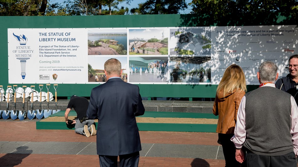 A promotional poster of the new museum with a man in a suit walking towards it.