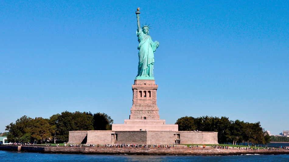The Statute of Liberty and visitors can be seen across the water.