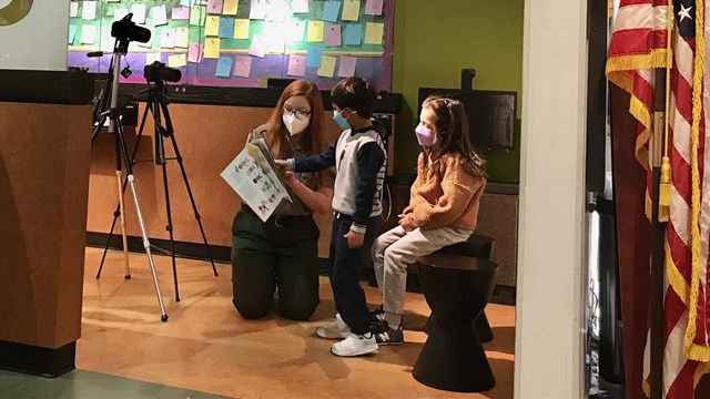 A picture of a ranger reading to two children