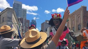 Rangers holding rainbow flags in front of a puppet of Marsha P. Johnson.