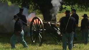 A Union cannon fires and flames belch from the muzzle.
