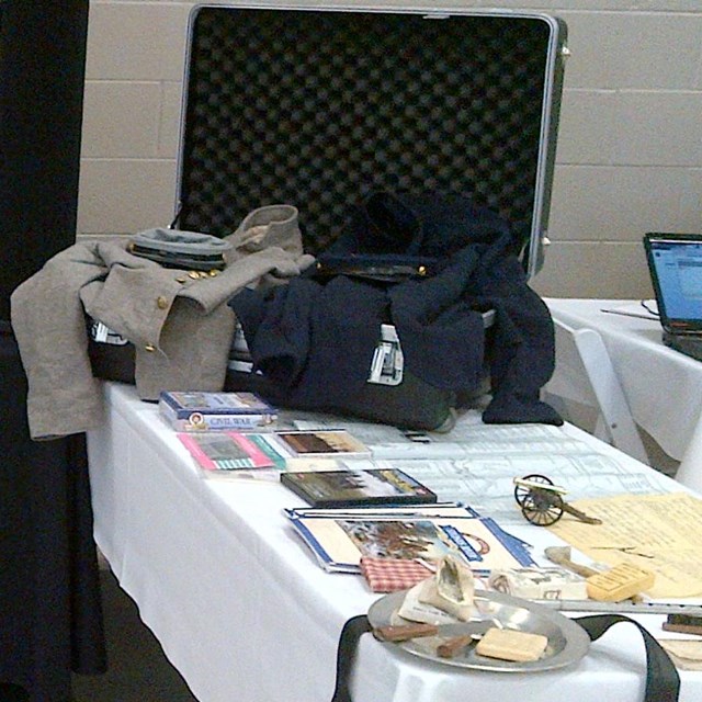 A display board is set up on a pair of tables, with an open trunk on one of them.