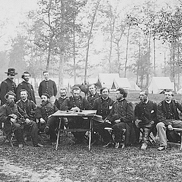 Union officers sit around a table in camp.