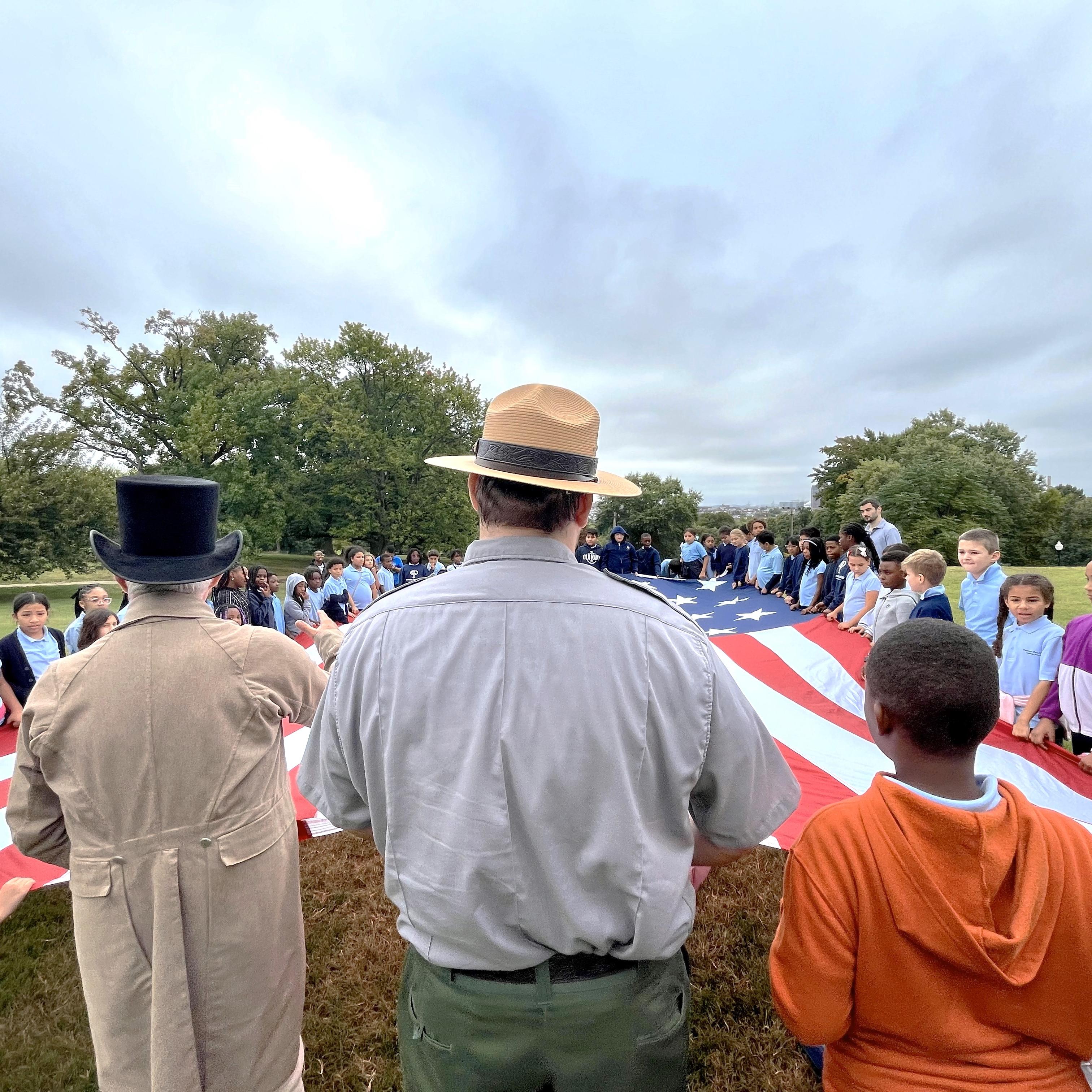 Visitors of all ages, holding the 30'x42' flag, with living historians and park rangers