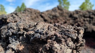 Close up of a jagged brown lava rock against a blue sky
