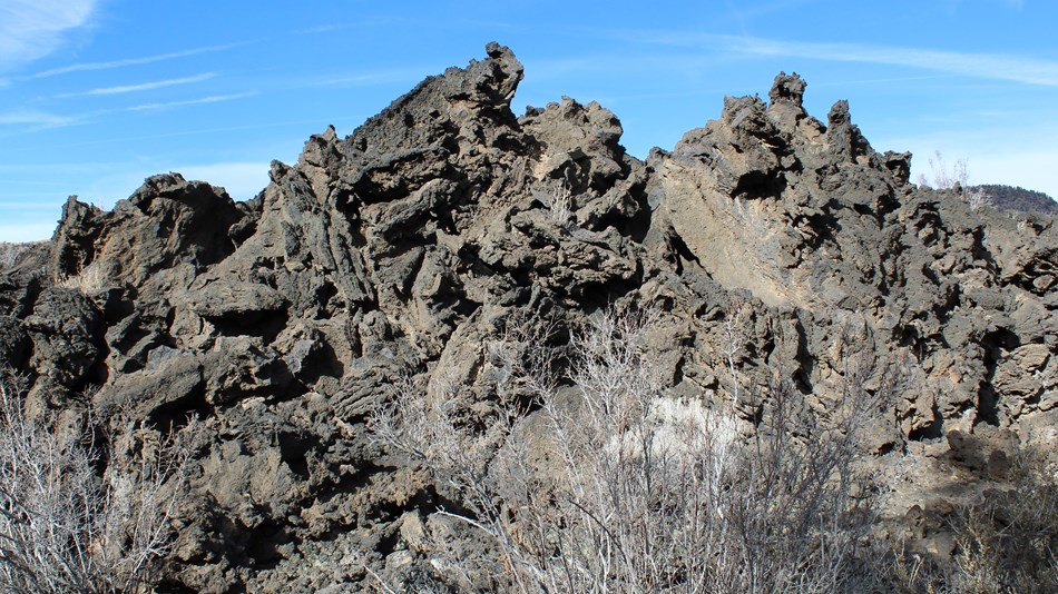 A jagged mass of black, cracked lava rock under a blue sky