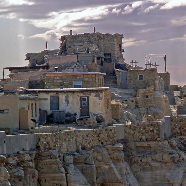Multi-story stone and mortar Hopi pueblo houses on top of an off-white stone mesa.
