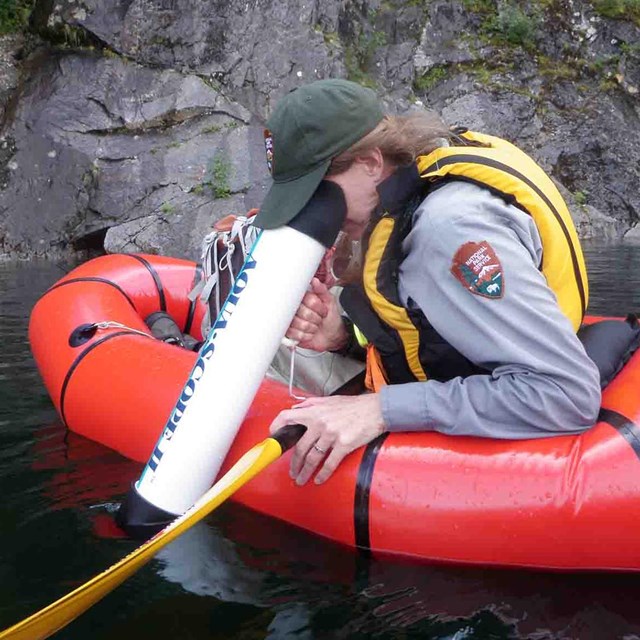 A ranger searches for submerged plants in a lake.