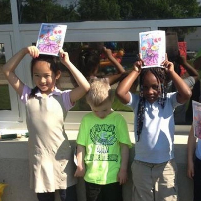 Children holding up drawings. NPS photo. 