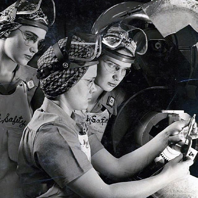 Four women (riveters) training in safety gear.