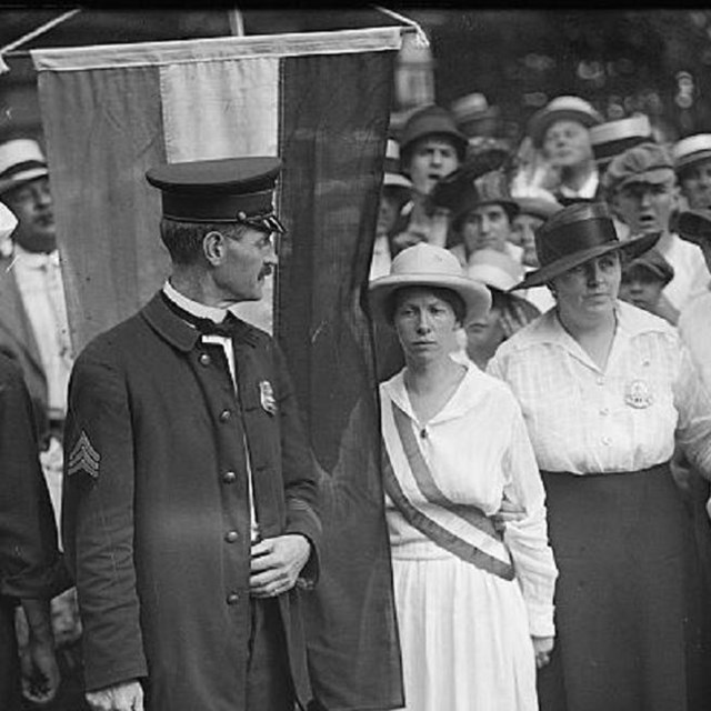 Suffragists picketing surrounded by police. 