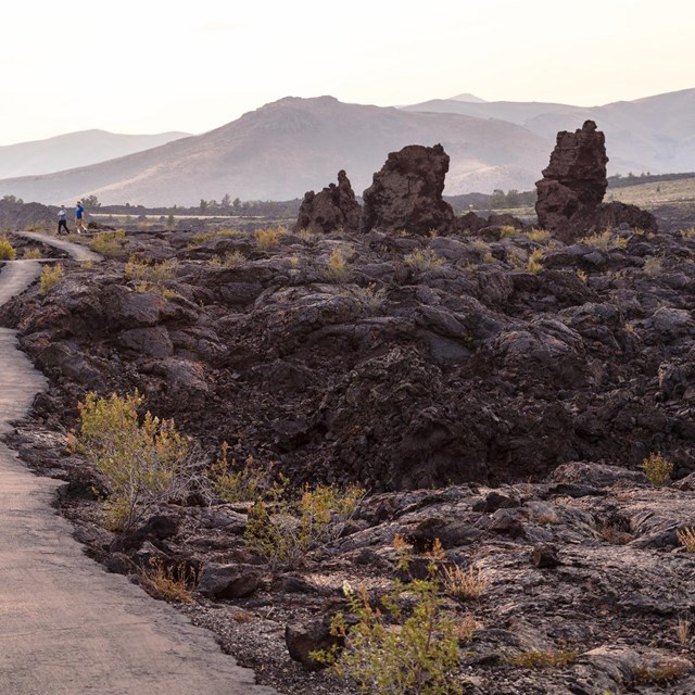 Hikers on a trail through lava flows