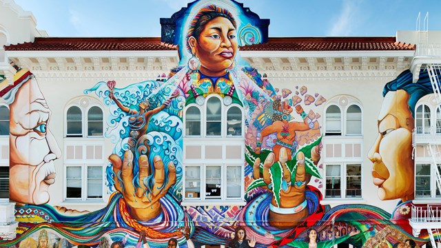 Large mural depicting abstract paintings of women on a white building