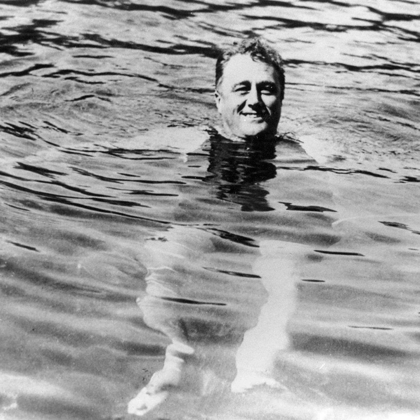 FDR in a swimming pool. His head is above the water and his legs are visible.