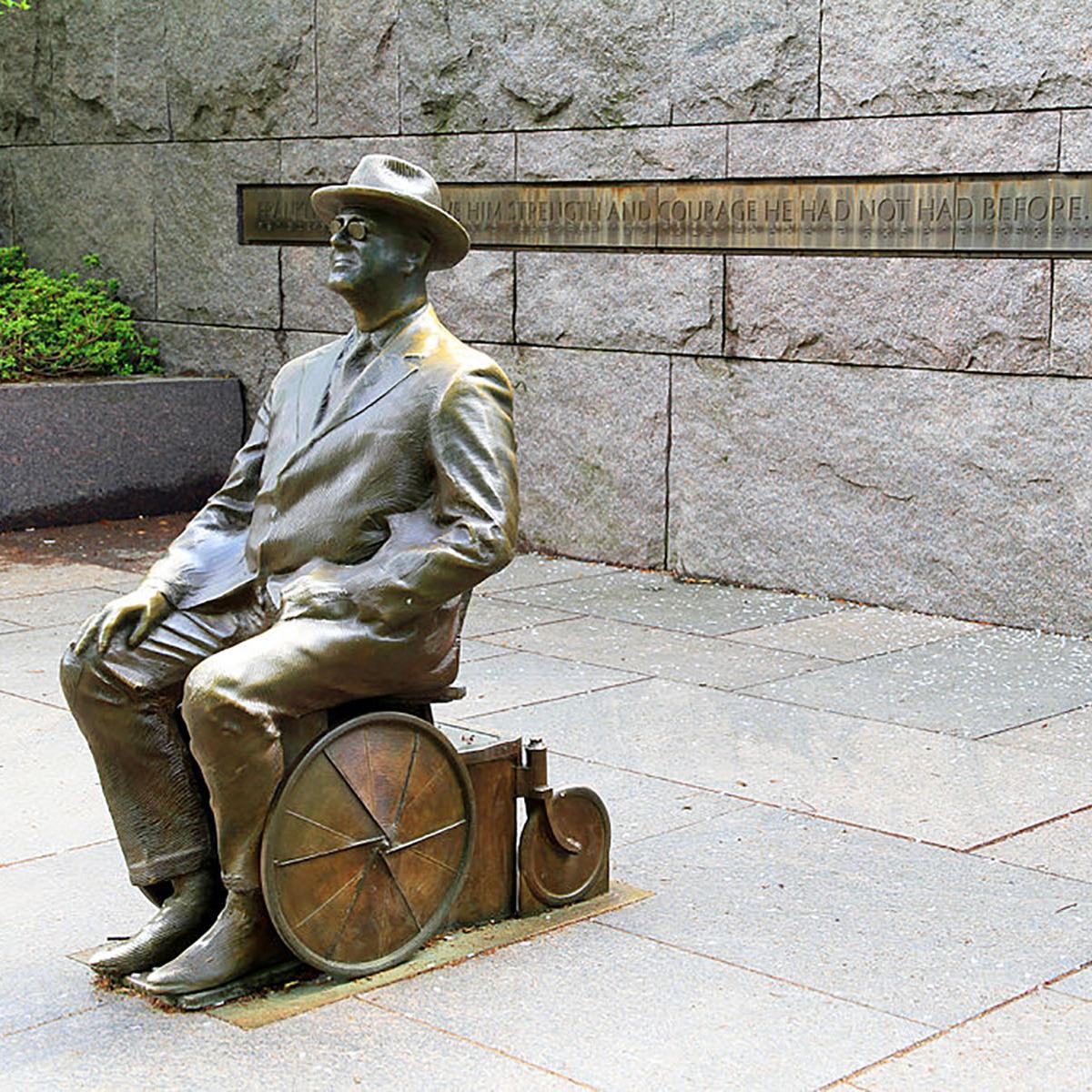 statue of a Franklin D. Roosevelt sitting in a kitchen chair style wheelchair