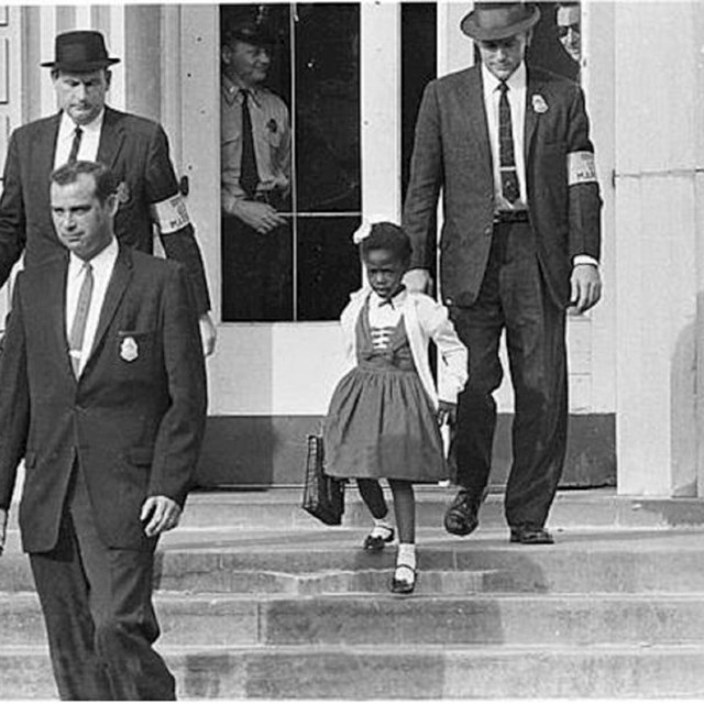 African American child walking down steps surrounded by white men