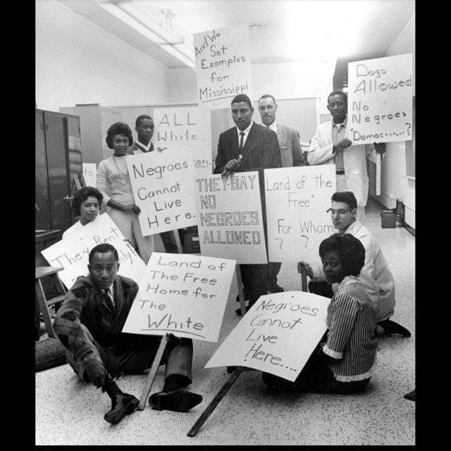 A group of African Americans in an office with signs reading 