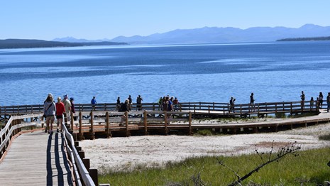 Visitors walking along the West Thumb Geyser Basin boardwalk.