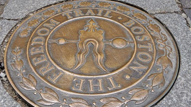 Circular bronze plaque reading "Freedom Trail" points towards a red brick path