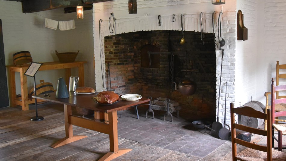 A large fireplace. A table sits in front of the fireplace, surrounded by tools and accessories. 