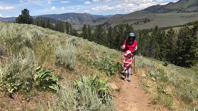 Daughter and mother hike up a trail along the Yellowstone River.