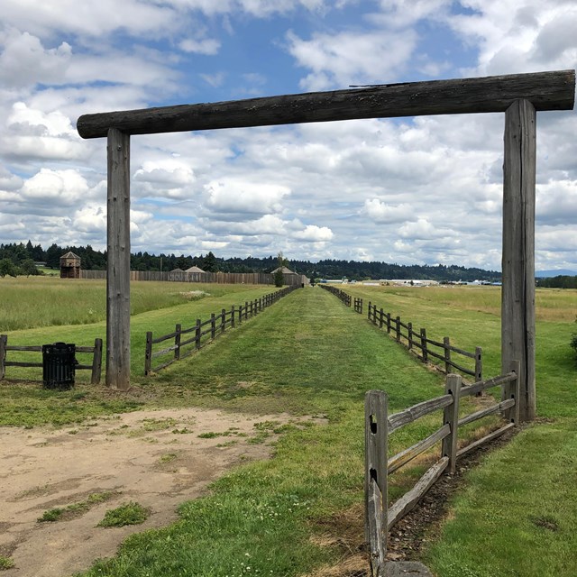 A wooden gate leading towards a grass covered path.