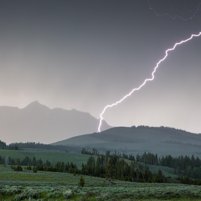 Lightning strikes Electric Peak as a dark storm rolls over the mountain.