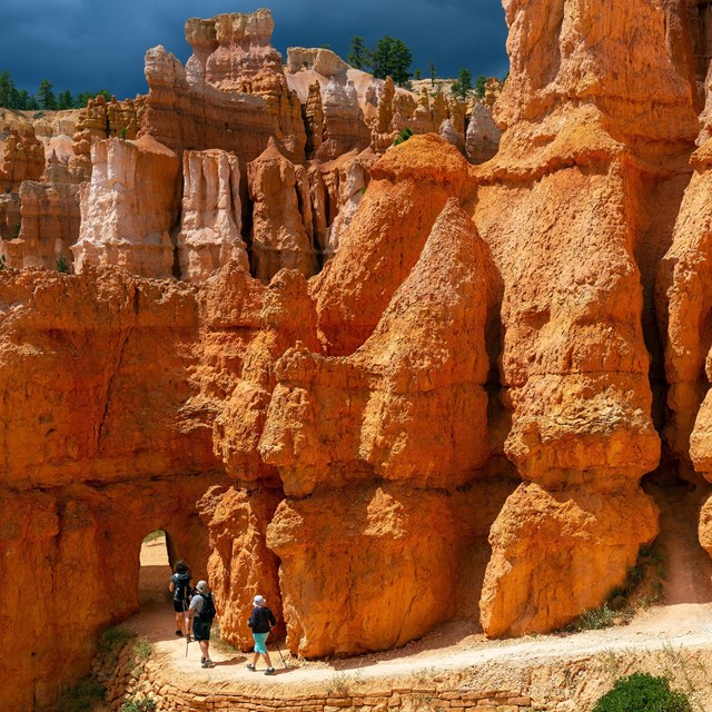 Hikers approach an archway on a hike.