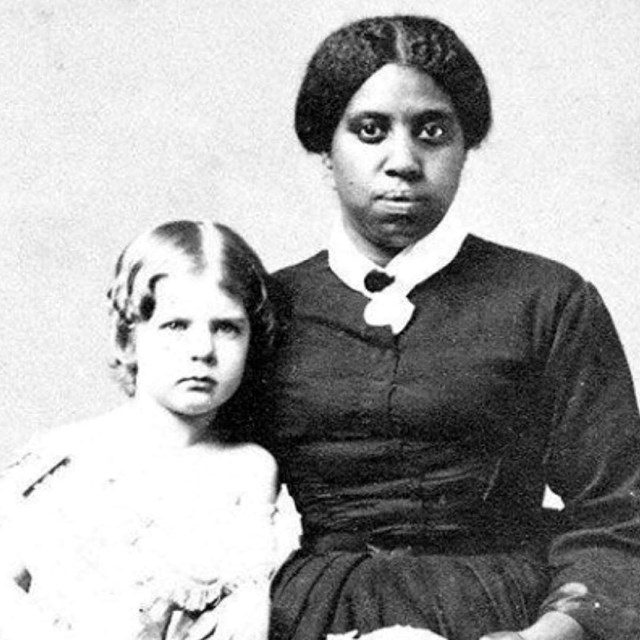 A black and white image of an enslaved woman with a white child.