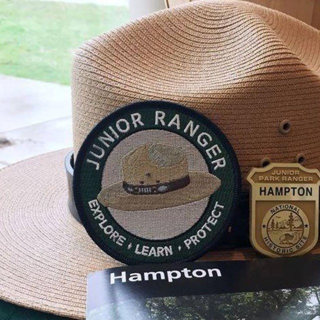 A park ranger hat with a junior ranger patch and badge resting on it.