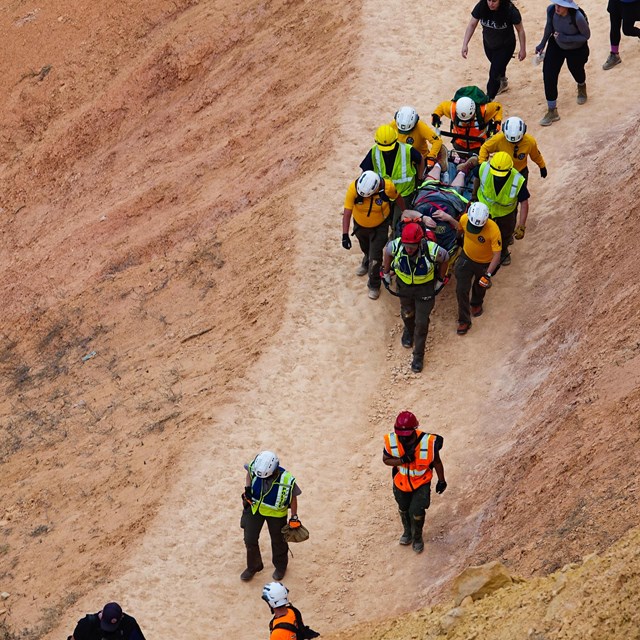 A group of people help carry a visitor out of the amphitheater on a stretcher.