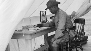 Black and White photograph of Theodore Roosevelt sitting at desk writing 