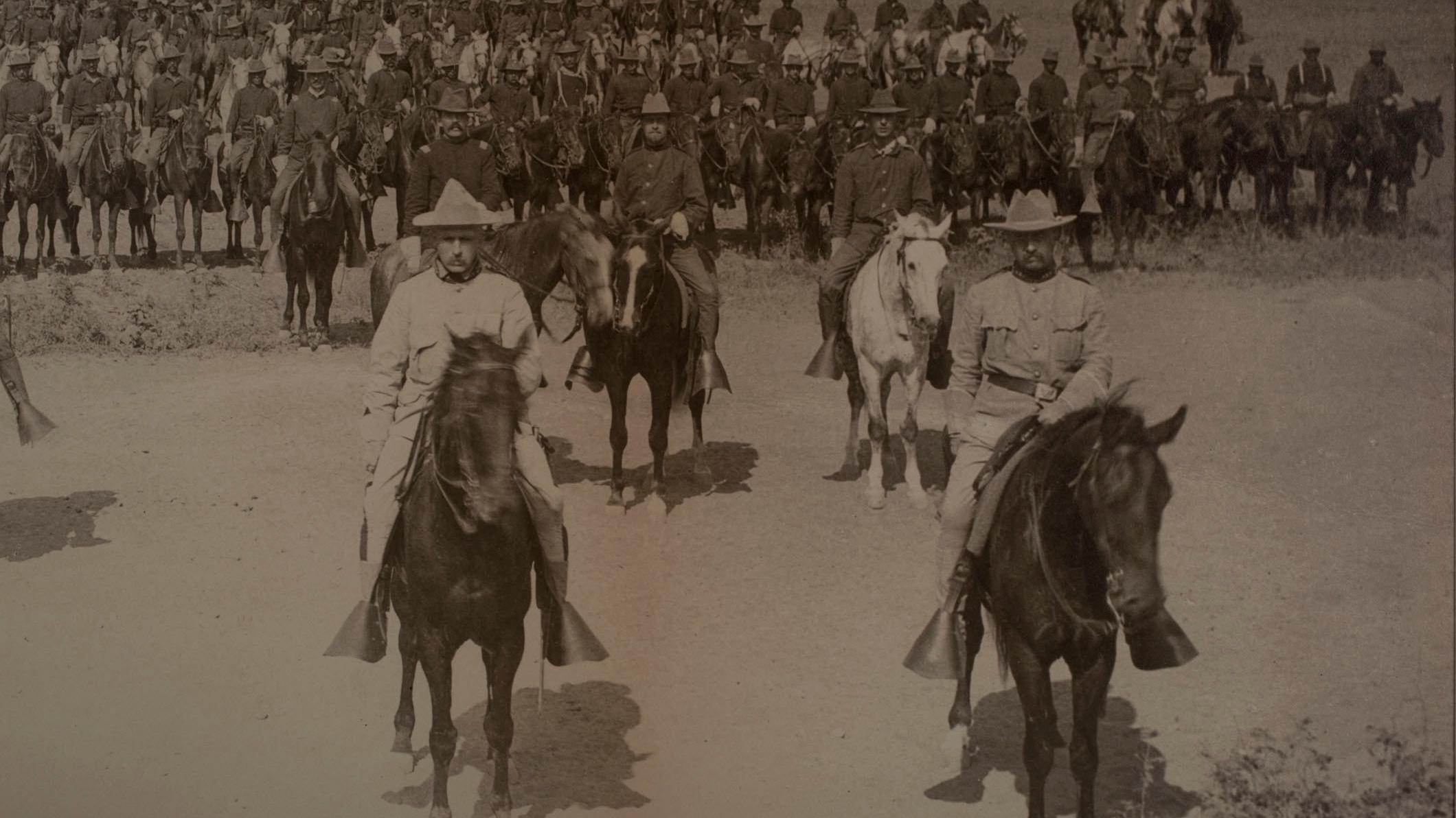 Sepia picture of TR on horseback in formation with other men riding horseback