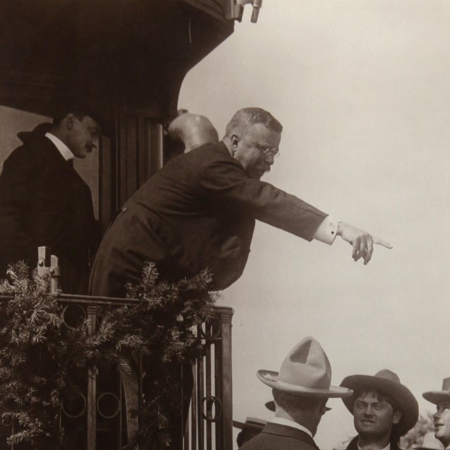Image of Theodore leaning out the back of a train car giving a speech. 
