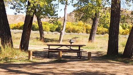 A little tent in prairie grasses with buttes in the background.