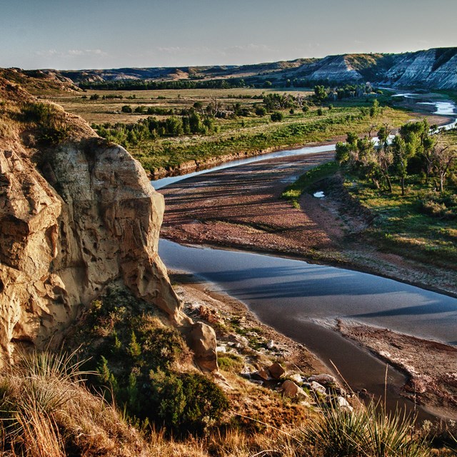 Long shadows forming with a weathered butte in the foreground overlooking the Little Missouri River