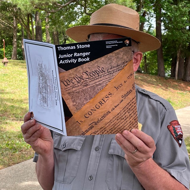 A park ranger holding up a junior ranger booklet.