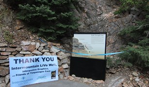 Thank you sign next to a blue ribbon strung across a large display on the mountain