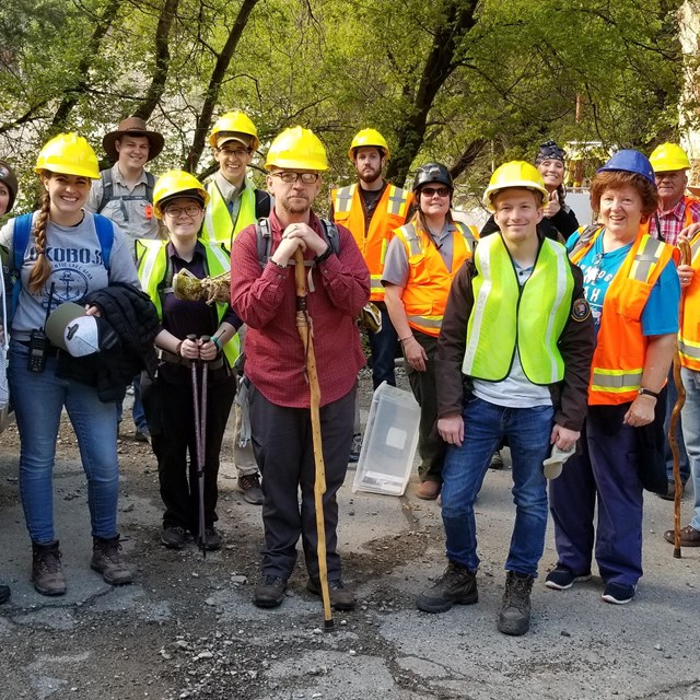 Group of volunteers with reflective vests, hard hats, and shovels. 