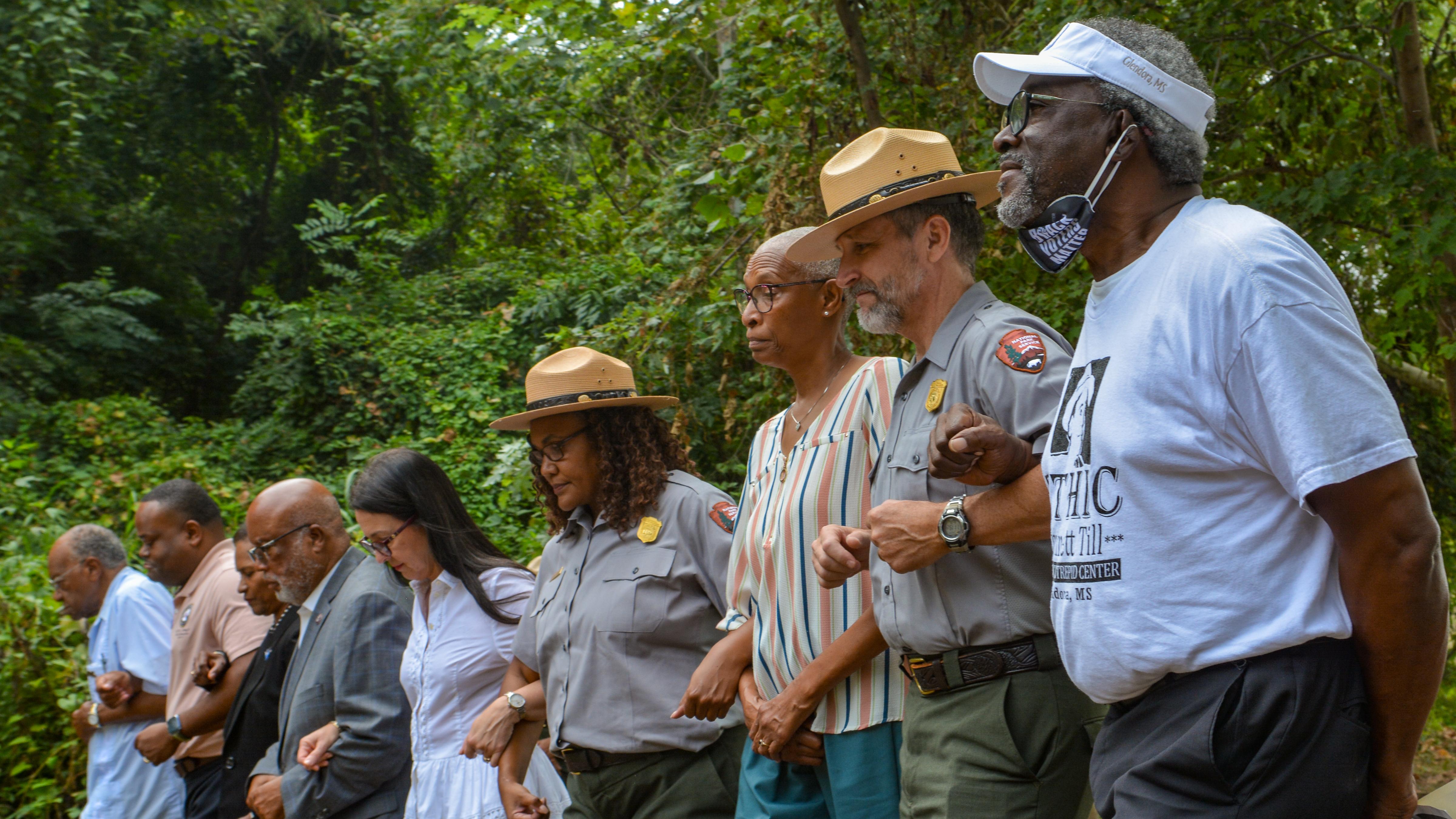 Park rangers walk arm in arm with several other people