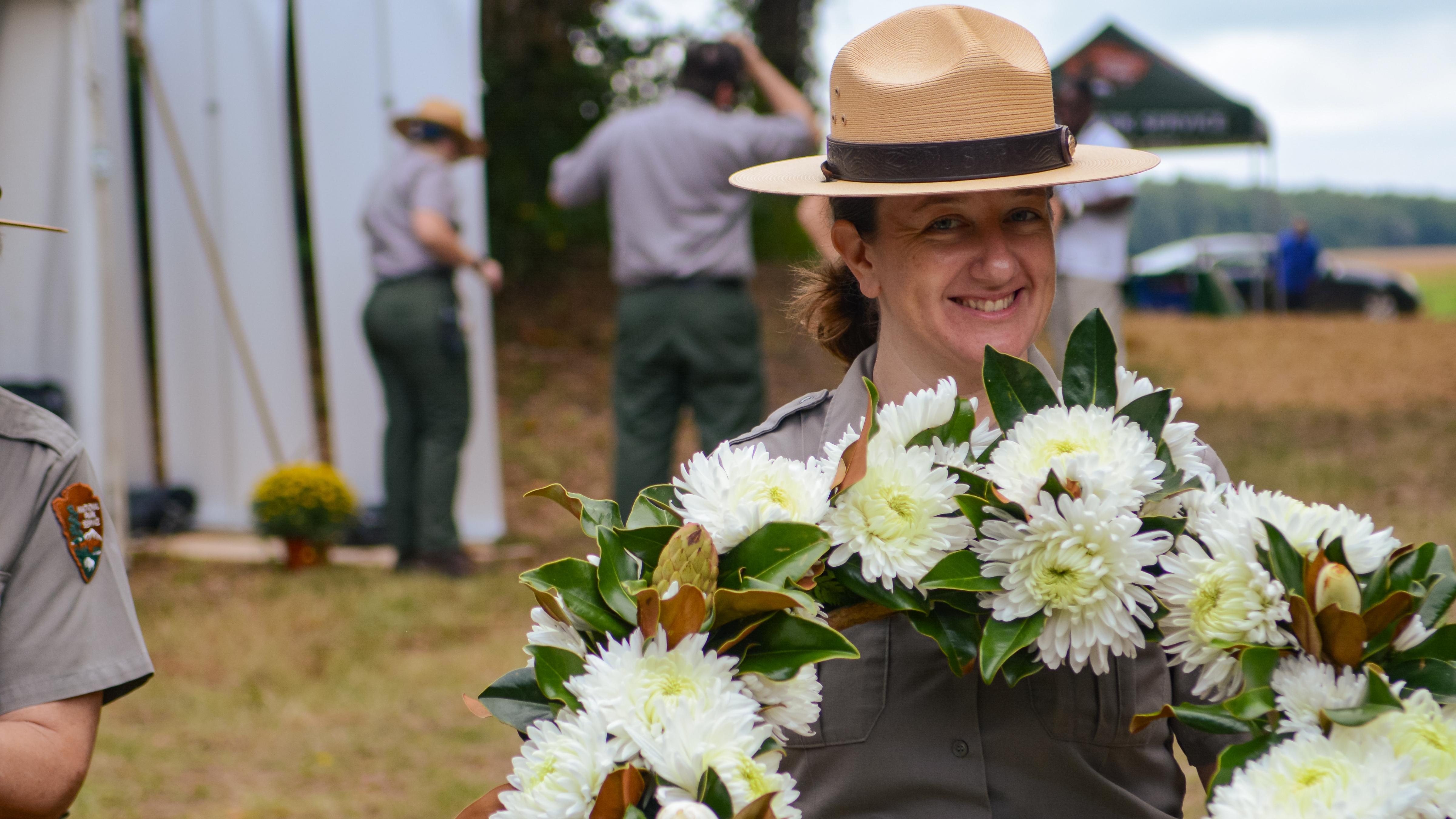 Park ranger holds a wreath with white flowers