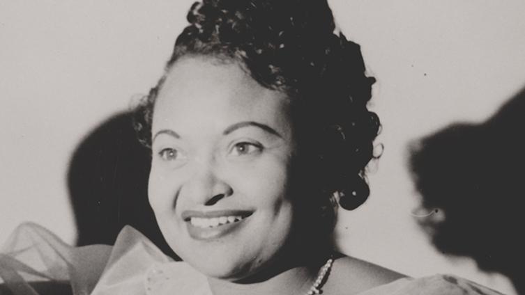 A black and white portrait of a woman smiling