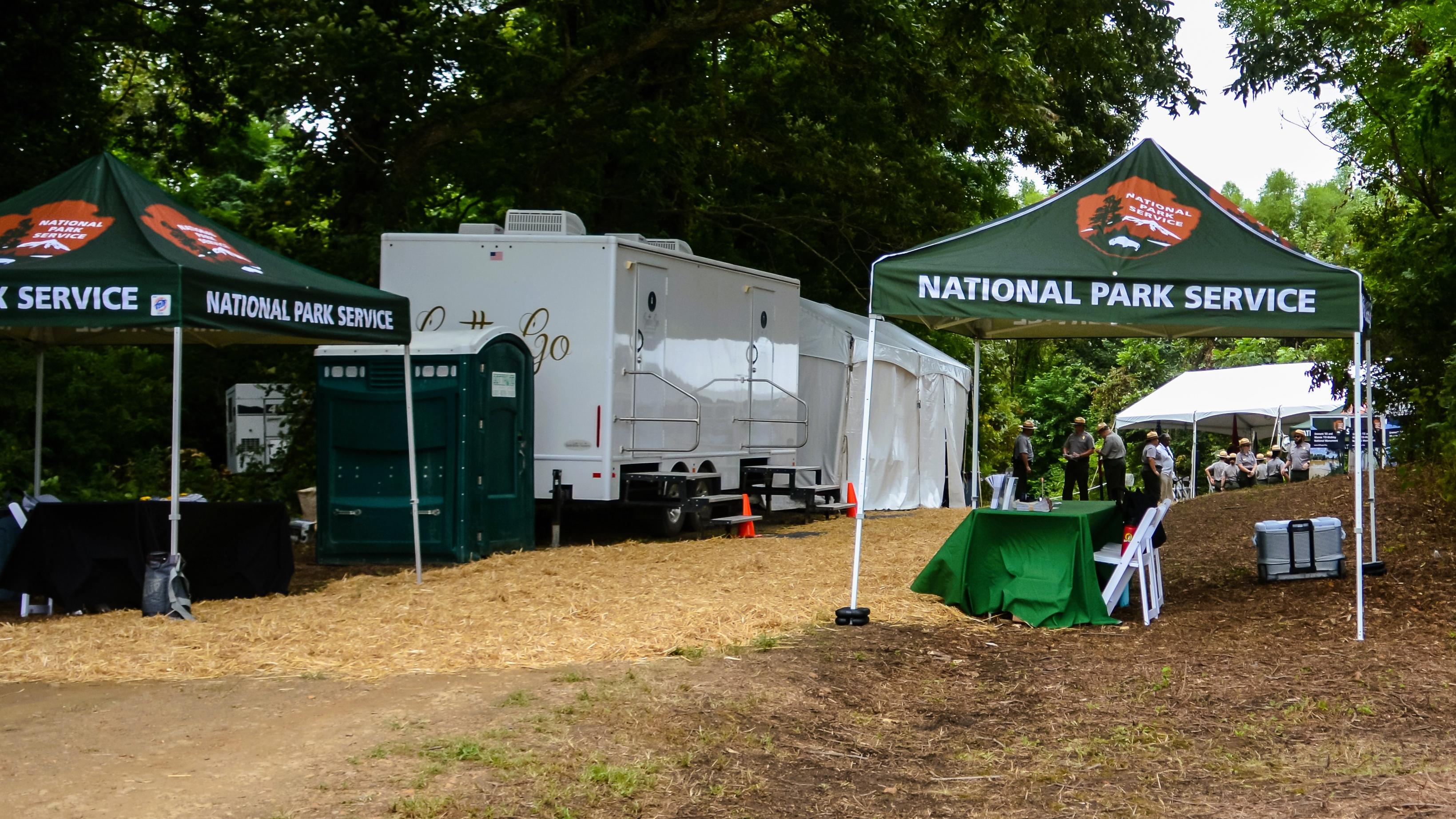 NPS tents and a historical marker sit in a grassy area