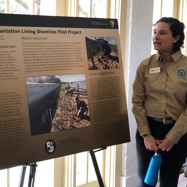intern stands next to a poster on living shorelines