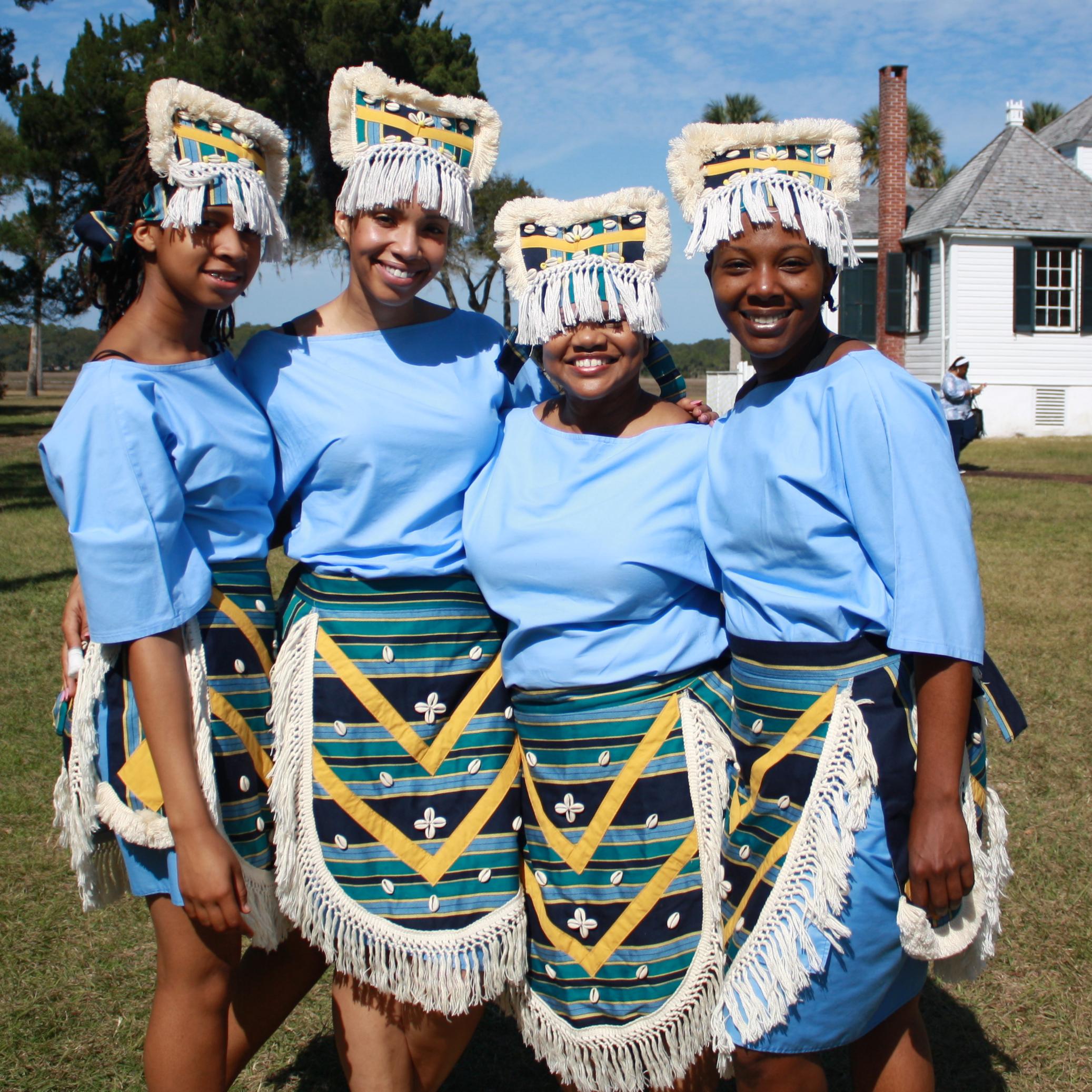 dancers pose with planters home in the background 
