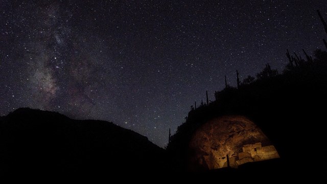 Illuminated cliff dwelling with the Milky Way Galaxy above. 