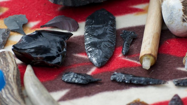 Arrowheads and flintknapping tools on colorful blanket