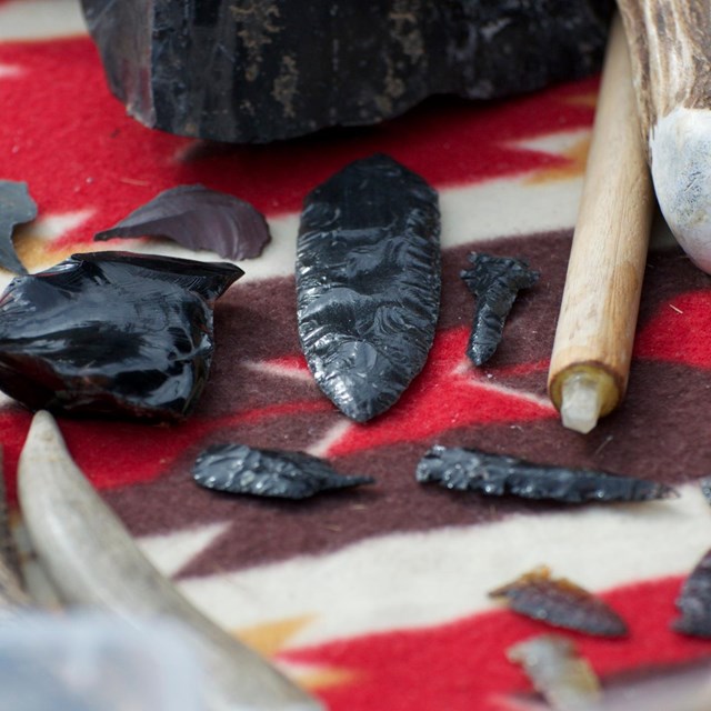 Arrowheads and flintknapping tools on colorful blanket