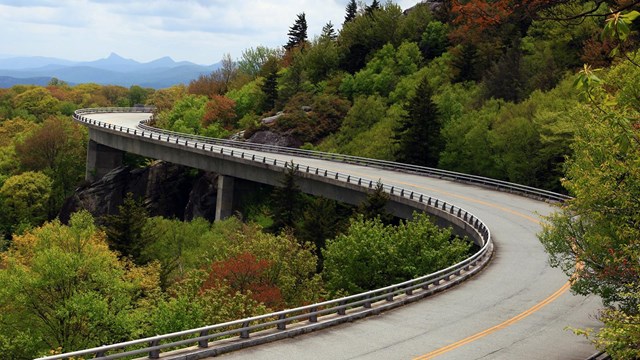 a curvy bridge along mountainous green hilside